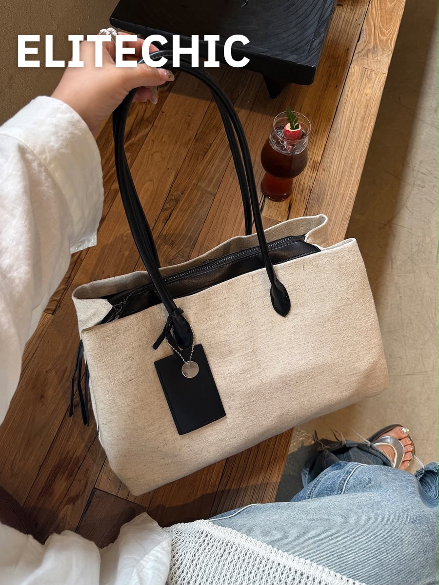 Tay cầm túi tote canvas kem quai đen trên bàn gỗ